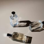 Three elegant perfume bottles casting shadows on a minimalist surface, captured in natural light.