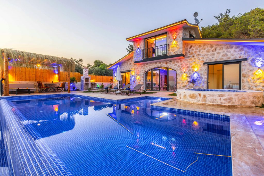 Elegant stone villa with illuminated facade, pool, and relaxing outdoor area.